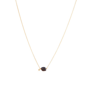 A simple gold necklace with a black tourmaline stone and tiny diamond charm, offering a symbol of purity and protection.